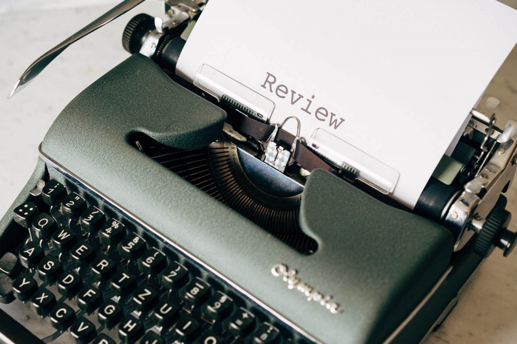 Eine antike Schreibmaschine mit einem Blatt Papier, auf dem das Wort 'Review' steht, um eine nostalgische Schreibszene einzufangen.