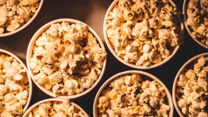 Mehrere mit Popcorn gefüllte Behälter, die an den traditionellen Snack erinnern, der bei Filmvorführungen genossen wird.